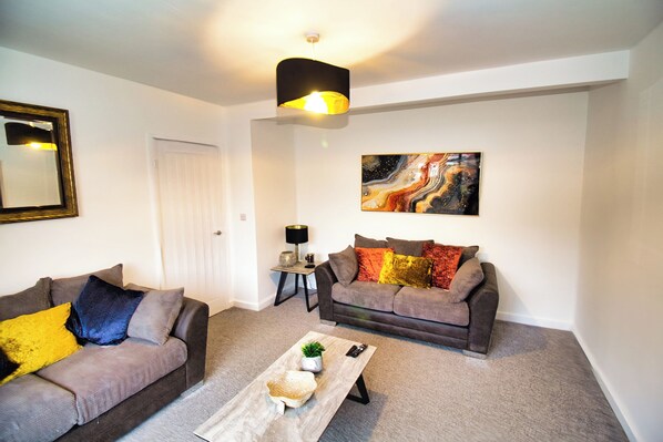 A living room with two sofas, a coffee table, a lamp, and a painting on the wall.
