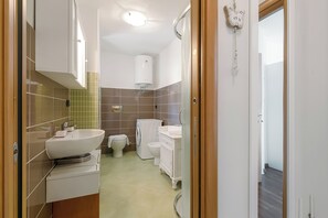 Een moderne badkamer met een wastafel, toilet en een wasmachine.