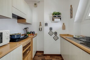 Una cocina compacta con armarios de madera, un microondas, una estufa y un lavamanos.
