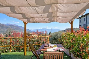 An outdoor seating area with a table, chairs, and a tablecloth.