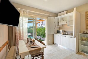 A modern kitchen with white cabinets, a dining area with a bench, and a sliding glass door leading to an outdoor patio.