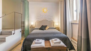 Quarto com cama, escada, parede com ilustração de sol e janela com cortinas.