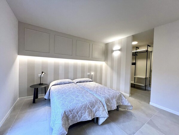 A modern bedroom with a bed, bedside tables, and a walk-in closet.