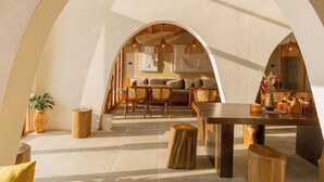 Un interior espacioso con techo alto, muebles de madera y una mesa de comedor central.
