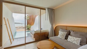 Una habitación moderna con una puerta corrediza de vidrio que da a un balcón con vistas a la playa y al mar.