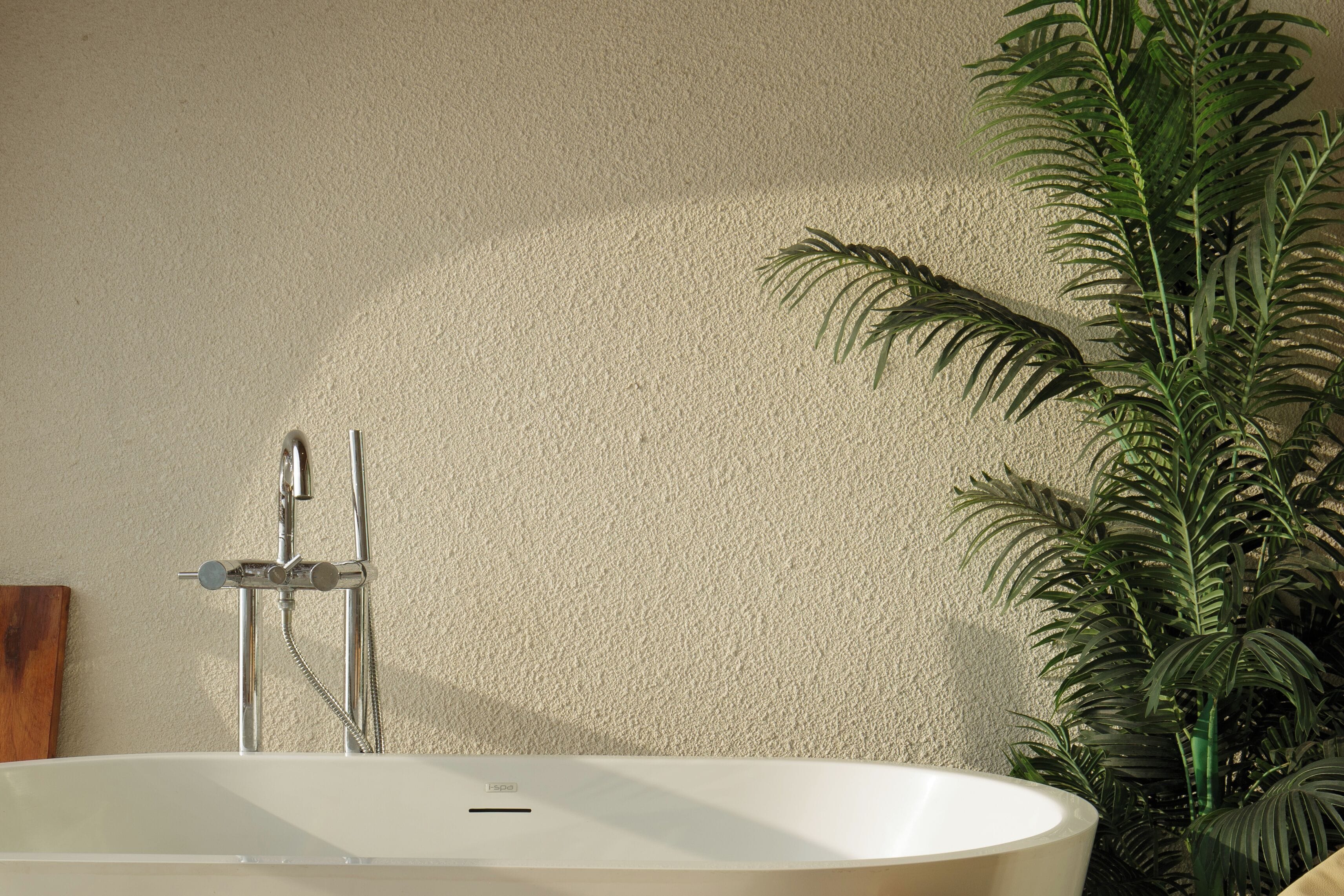 A bathroom with a bathtub, a shower, and a potted plant.