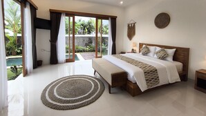 Ein geräumiges Schlafzimmer mit einem großen Bett, einem hölzernen Kopfteil, einem Nachttisch mit Lampe und Blick auf ein Schwimmbecken durch Glastüren.
