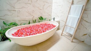 A bathroom with a freestanding bathtub filled with rose petals, a wooden ladder, and a small sink. - Elden Ubud View Private Villas by EPS (Ubud)