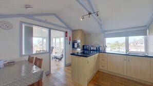 A modern kitchen with wooden cabinets, a black countertop, and a view of the outside. - G23 Norda, Riviere Towans (Hayle)