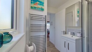 A modern kitchen with white cabinets, a stainless steel range hood, and a window with a view.
