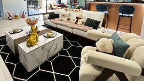 Un salon moderne comprenant un canapé, une table basse et un coin bar avec des tabourets.