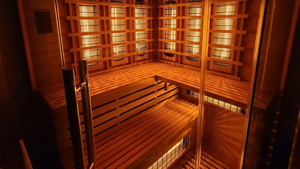 Un sauna avec des bancs en bois et un appareil de chauffage fixé au plafond.