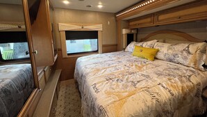 Een slaapkamer met een bed, een raam en een spiegel.