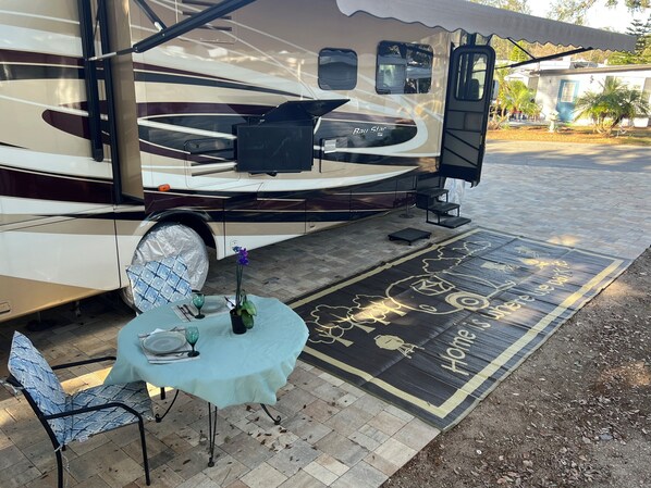 Un véhicule récréatif doté d’un espace abrité, d’une table avec des chaises et d’un tapis décoratif.