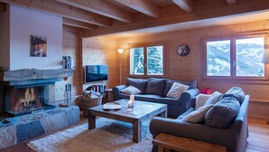 A cozy log cabin interior with a fireplace, a sofa, a coffee table, and a TV.