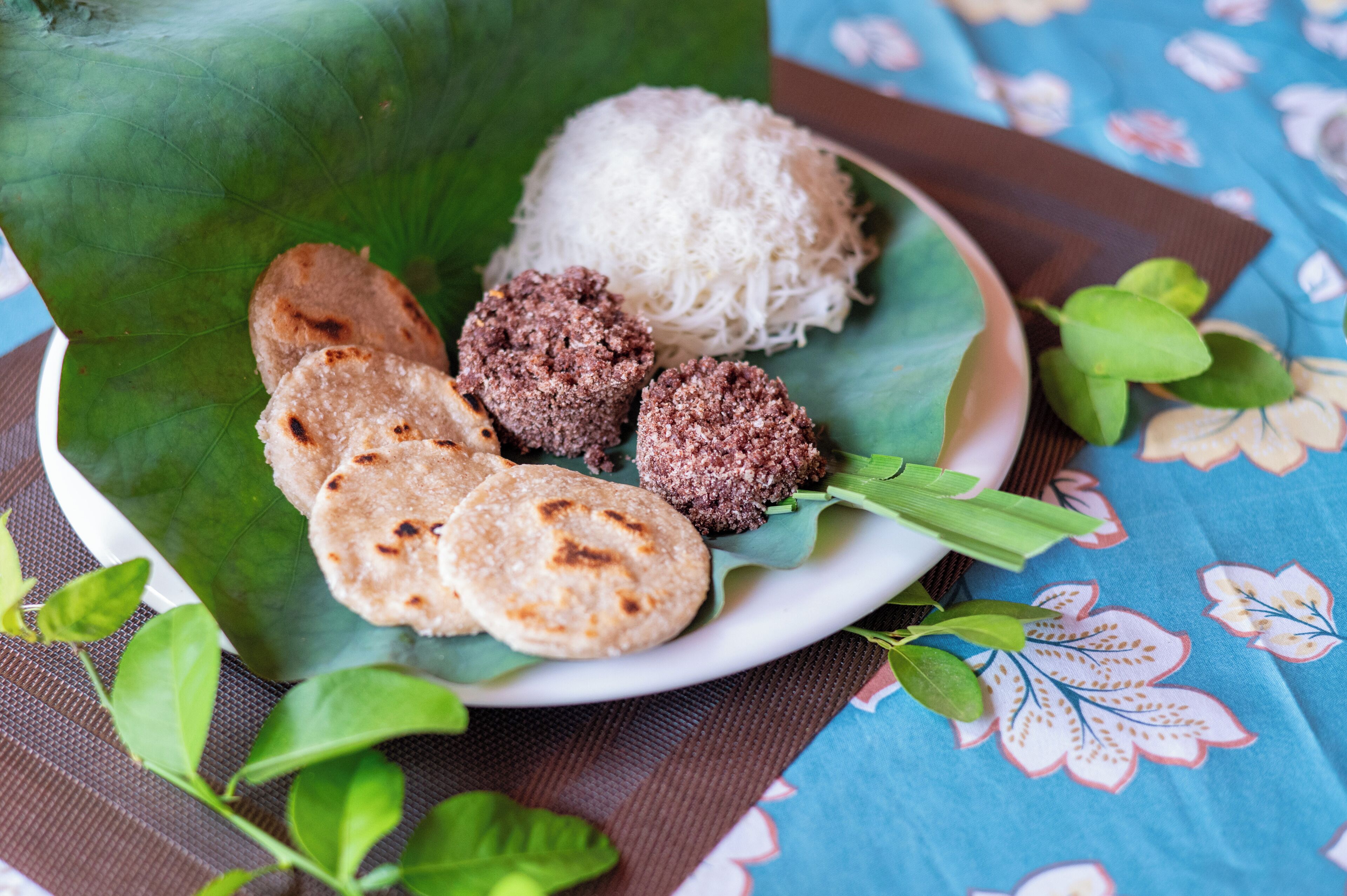 A plate of food with rice, flatbreads, and a meat dish on a leaf.