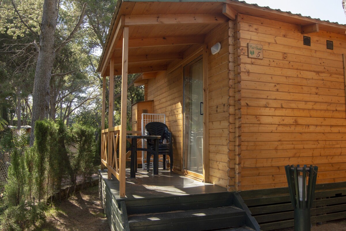 Une cabane en bois avec une véranda, une table et des chaises.