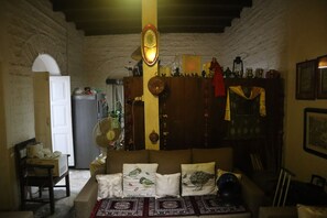 A cozy living room with a sofa, a wooden cabinet, and a fan. - The Bicknell's Nest (Kalimpong)