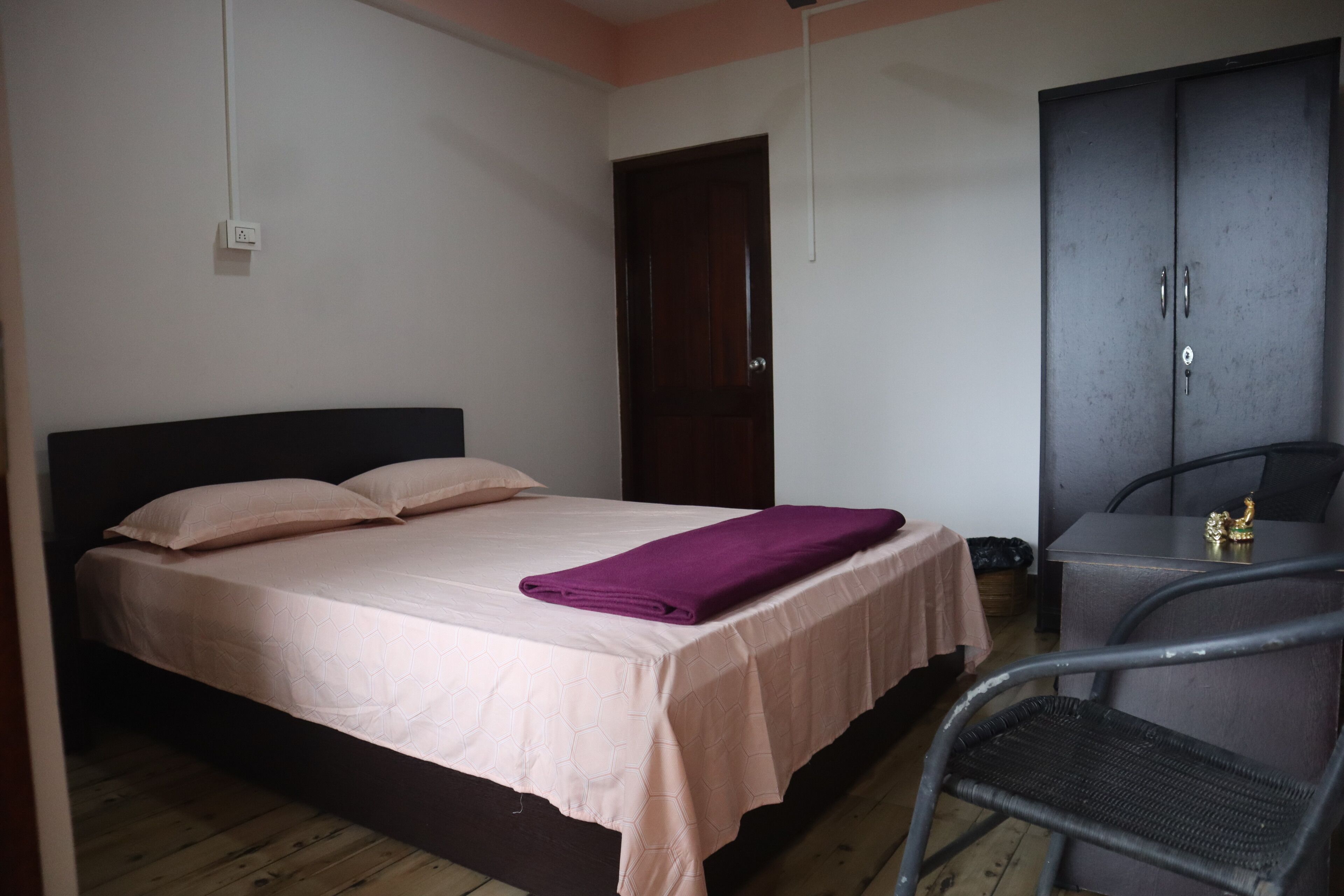 A bedroom with a bed, a chair, a wardrobe, and a table.