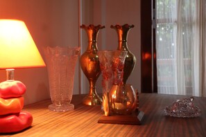 A wooden table with various glass vases and a candle holder. - The Bicknell's Nest (Kalimpong)