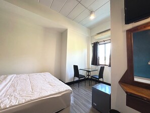 A hotel room with a bed, a small table with two chairs, a window with curtains, and a television mounted on the wall. - Zimbei Cozytel Khaolak (Takua Pa)
