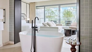 Un baño moderno con una bañera independiente, un ventanal grande y un balcón con mobiliario exterior.