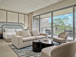 Une chambre d’hôtel moderne dotée d’un grand lit, d’un canapé, d’une table basse et d’un balcon aménagé avec du mobilier d’extérieur.