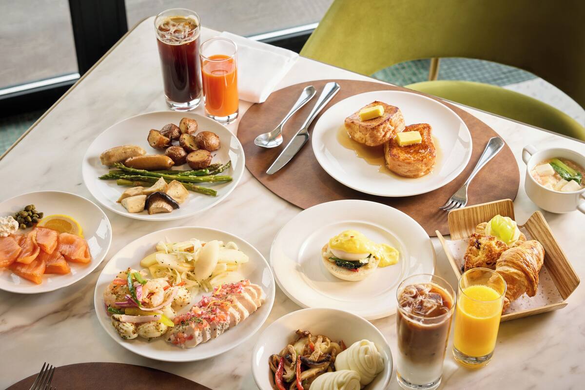 Une table de petit-déjeuner avec différents plats, boissons et couverts.
