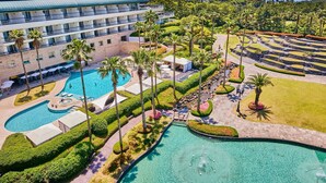 Un resort con varias piscinas, palmeras y un edificio grande con balcones.