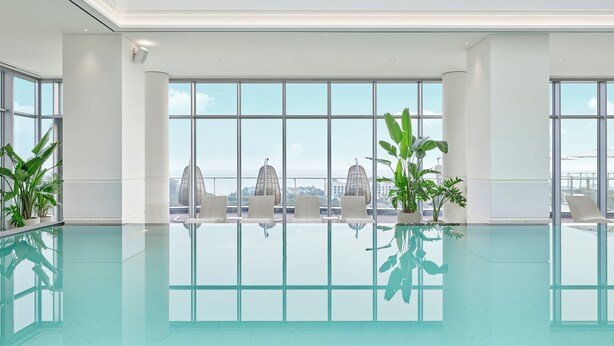 Una piscina interior moderna con amplios ventanales que ofrecen vistas a la ciudad.