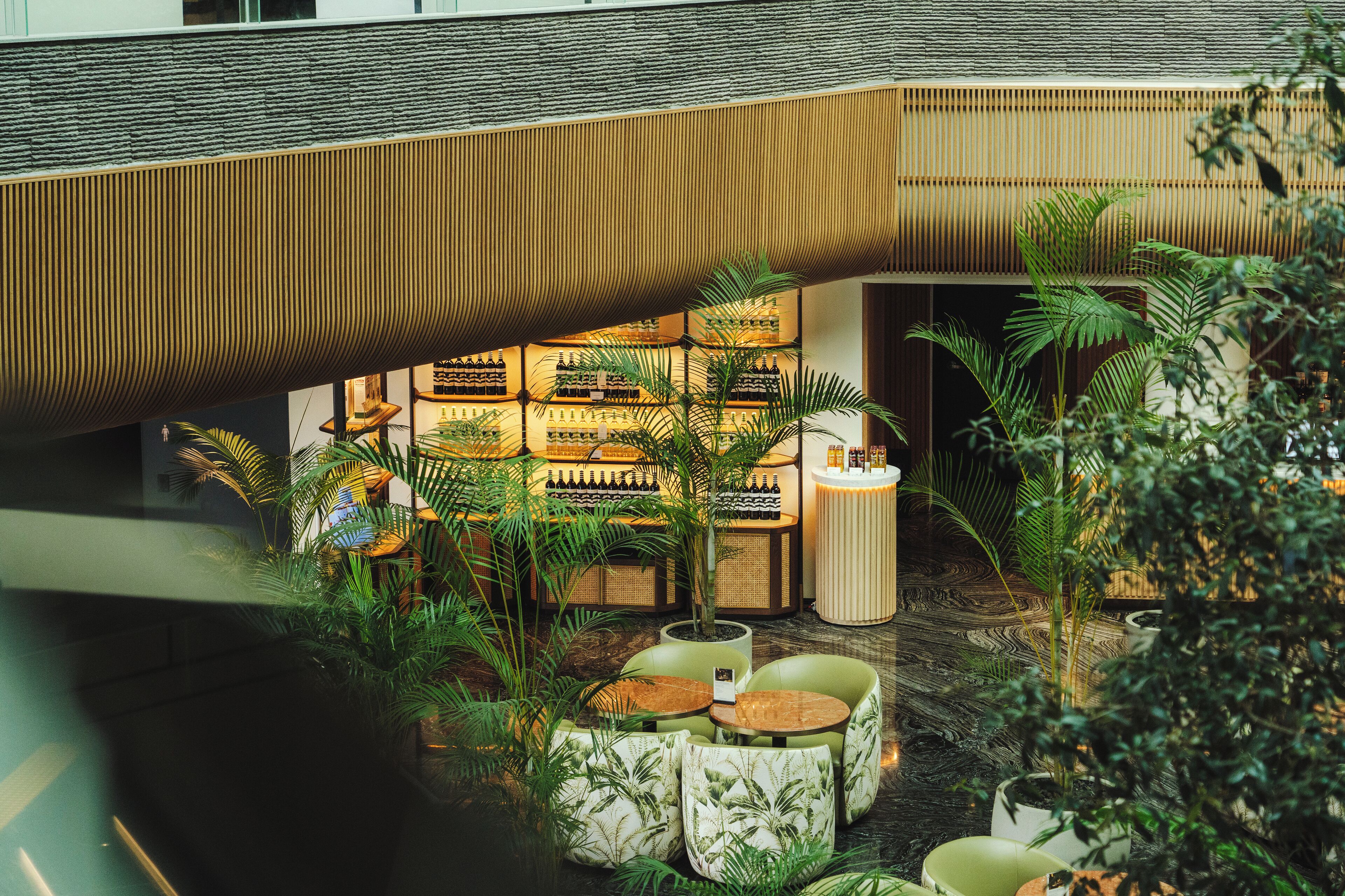 An indoor area with seating, plants, and a bar with bottles.