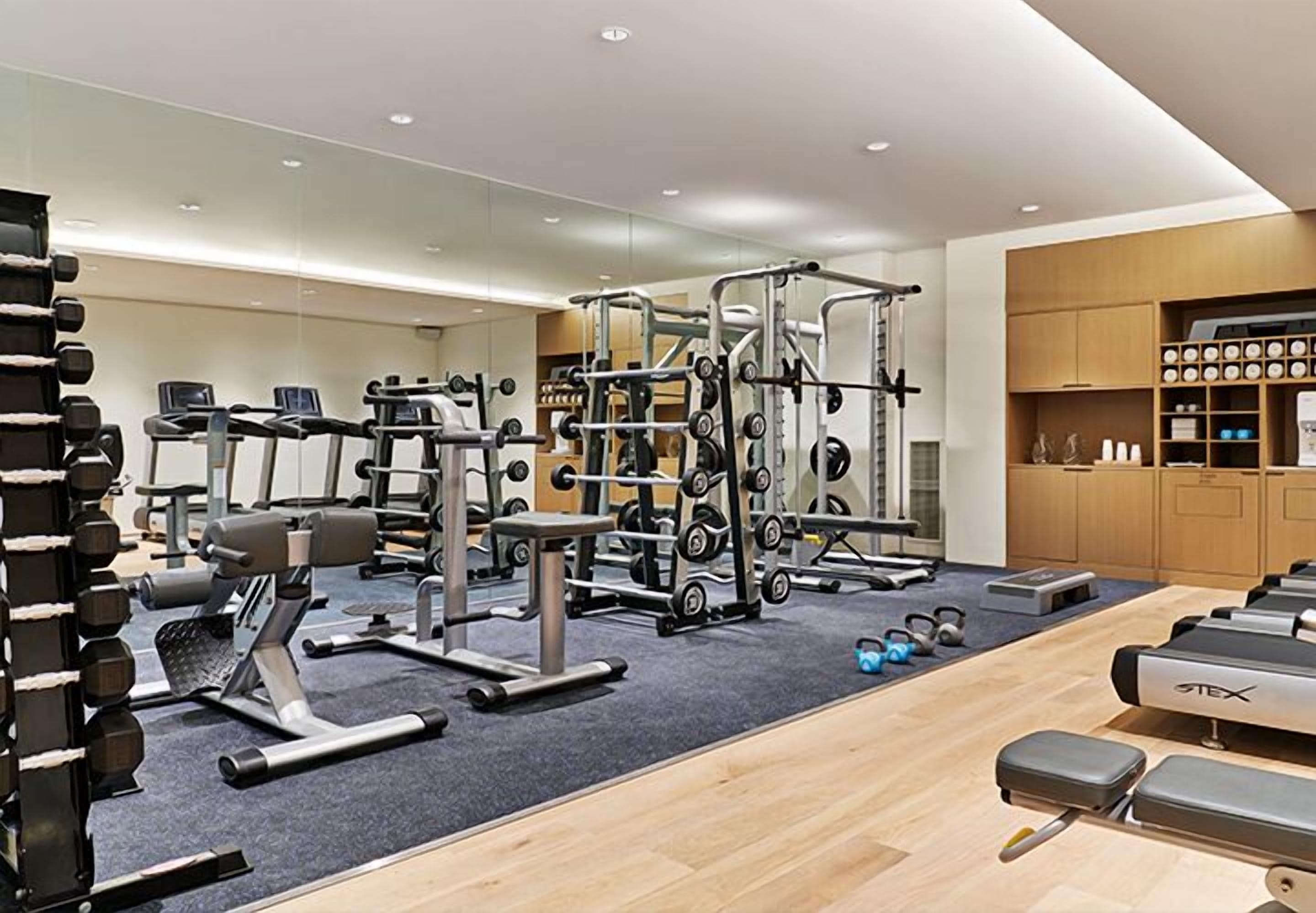 Un gimnasio moderno con diversos equipos de ejercicio, incluyendo cintas de correr, máquinas de pesas y pesas libres.
