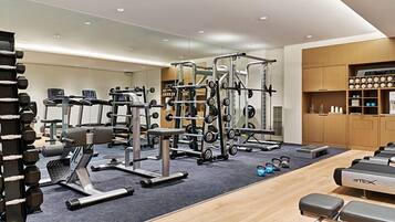Un gimnasio moderno con diversos equipos de ejercicio, incluyendo cintas de correr, máquinas de pesas y pesas libres.