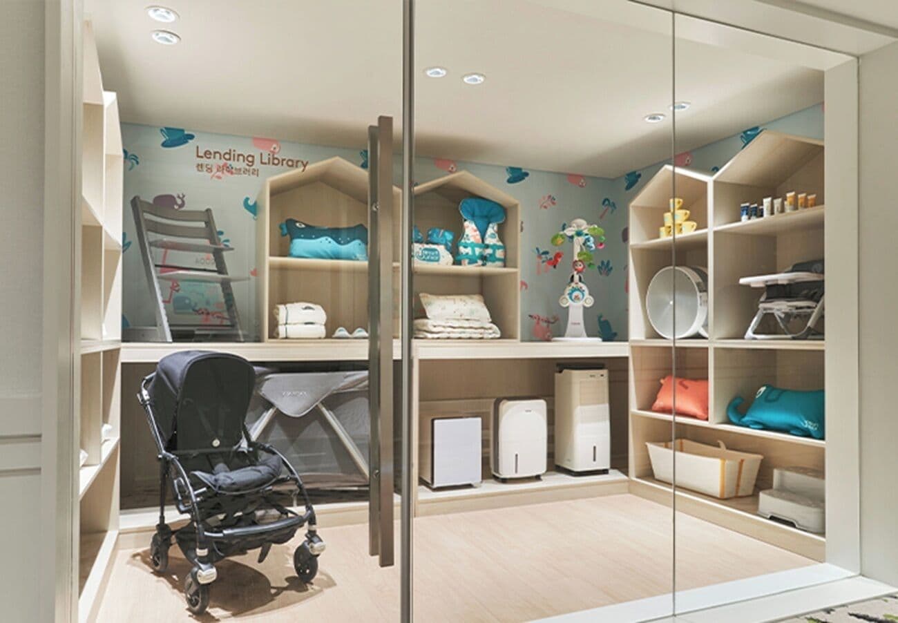 Une pièce avec une poussette pour bébé, des étagères remplies de produits pour bébés et une fresque murale.