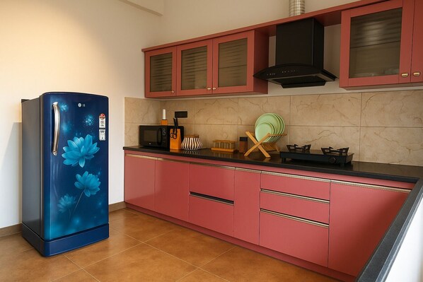 A kitchen with a blue refrigerator, red cabinets, a microwave, and a gas stove. - Dlite Rivera  (Bengaluru)