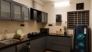 A modern kitchen with grey cabinets, a stainless steel sink, a microwave, a stove, and a black refrigerator with a floral design. - Dlite Rivera  (Bengaluru)