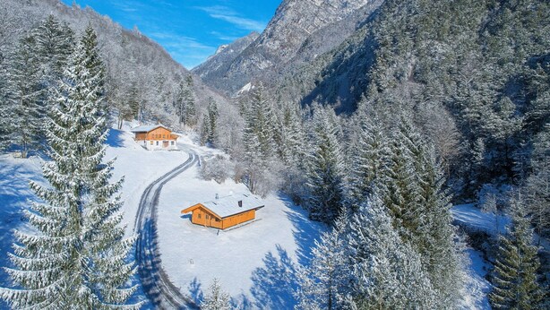 A snow-covered mountain landscape with a wooden cabin and a ski trail.