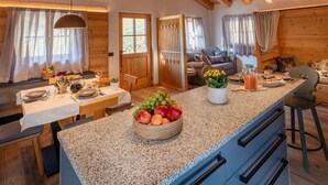 A cozy kitchen with a granite countertop, wooden cabinets, and a dining area with a table set for two.