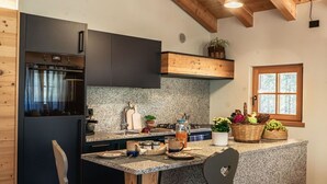A modern kitchen with a granite countertop, wooden ceiling beams, and a built-in oven.