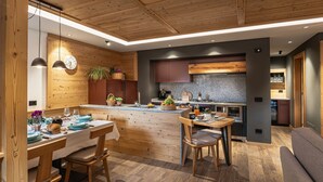 Une cuisine moderne agrémentée de touches de bois, dotée d’un îlot central et d’un coin repas avec des meubles en bois.