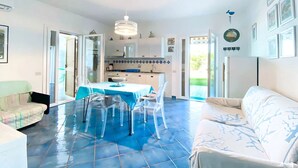 Una cucina moderna con mobili bianchi, un pavimento piastrellato di blu e un'area pranzo con tavolo e sedie.