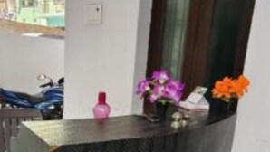 A reception desk with a dark, textured surface, a wooden door with a glass panel, and a tiled floor. - Hotel Mahadev inn (Varanasi)