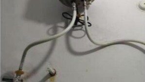 A white cylindrical object with a label, connected to a wall by wires. - Hotel Mahadev inn (Varanasi)