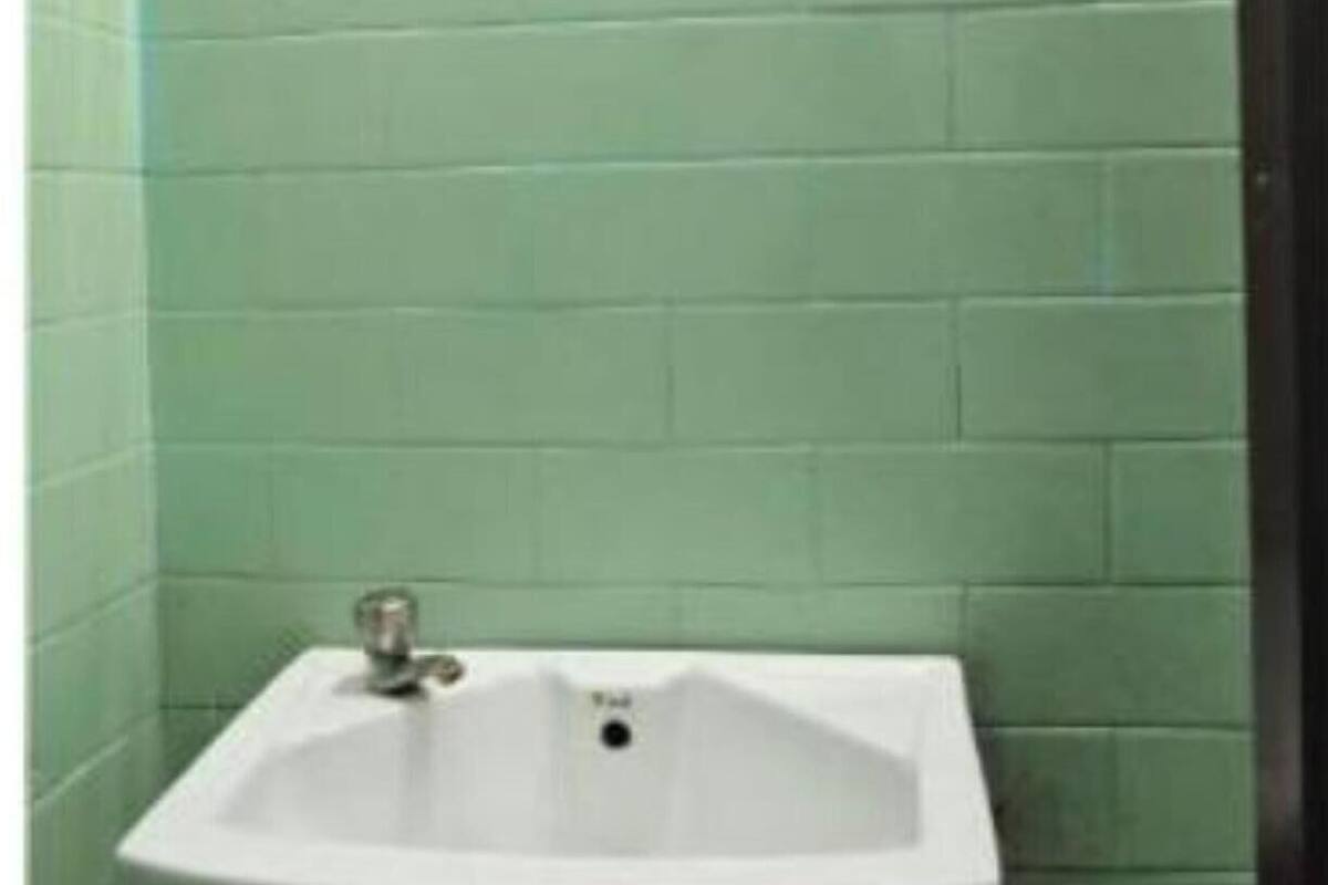 A bathroom with a white sink, green tiled walls, and visible plumbing.
