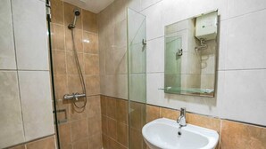 A bathroom with a glass shower enclosure, a white sink, and a mirror above it. - Collection O metroploitian park Serviced Apartmen (Bekasi)