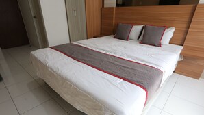 A large bed with a white and gray bedspread, a wooden headboard, and two pillows. - Collection O metroploitian park Serviced Apartmen (Bekasi)