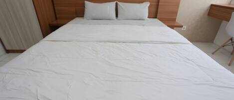 A neatly made bed with white bedding in a hotel room.
