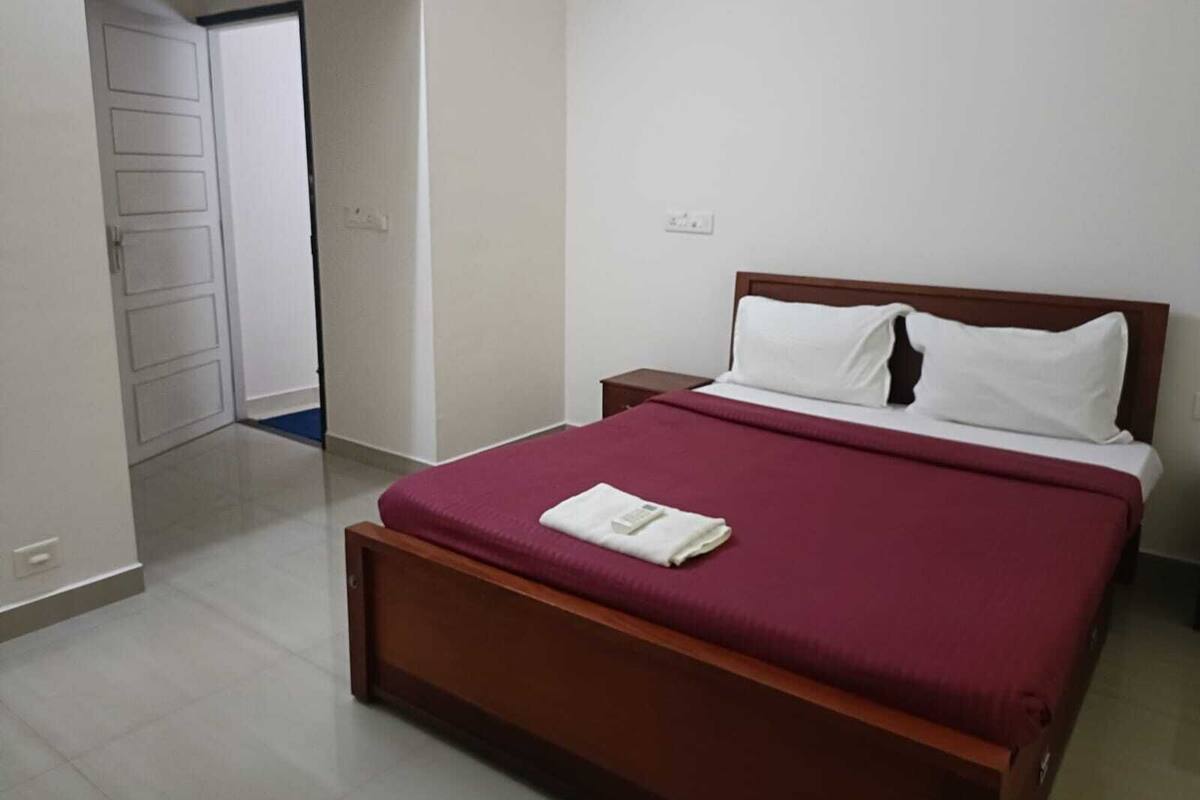 A bedroom with a wooden bed, white bedding, and a red blanket.