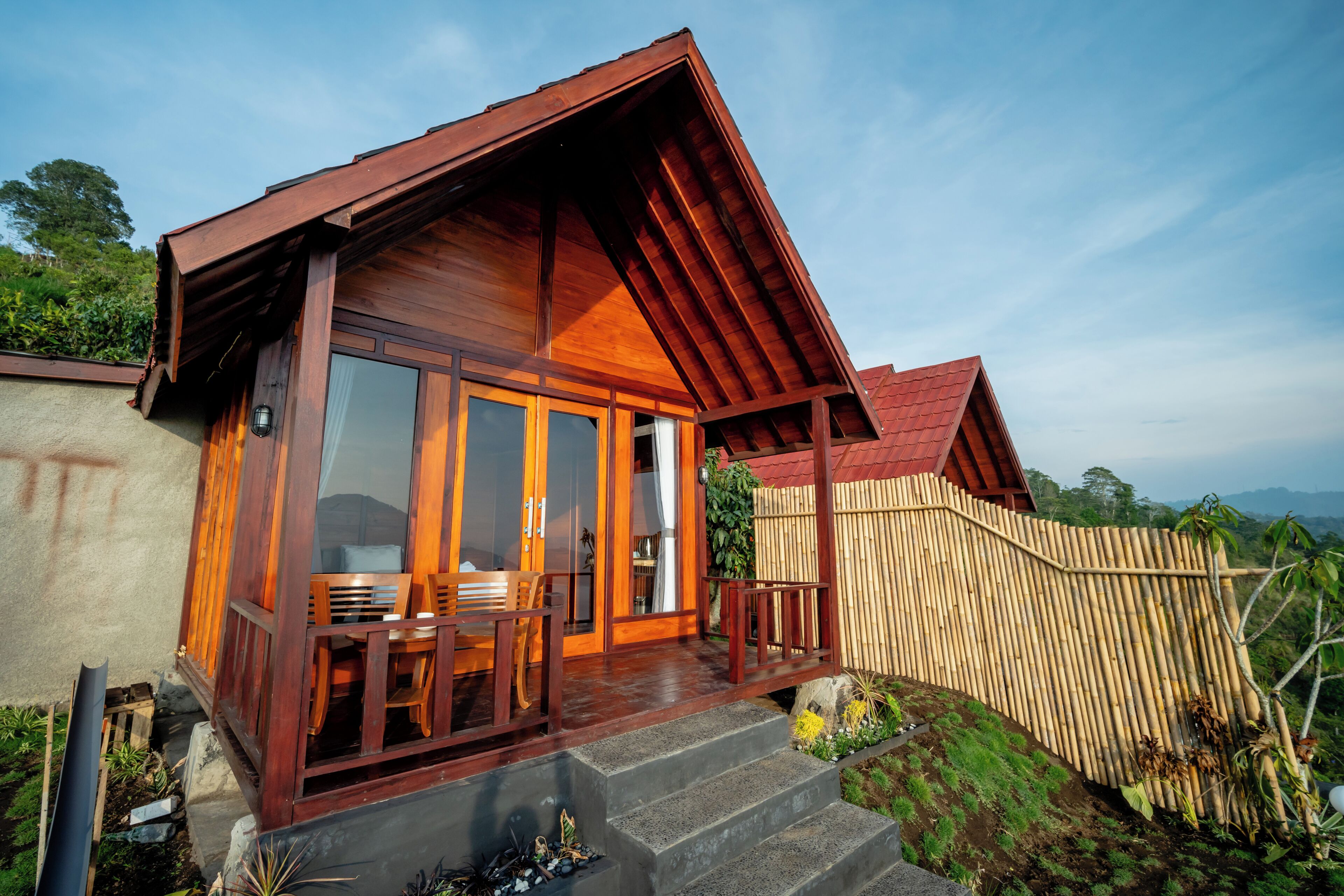 A wooden house with a porch, large windows, and a view of the surrounding landscape.