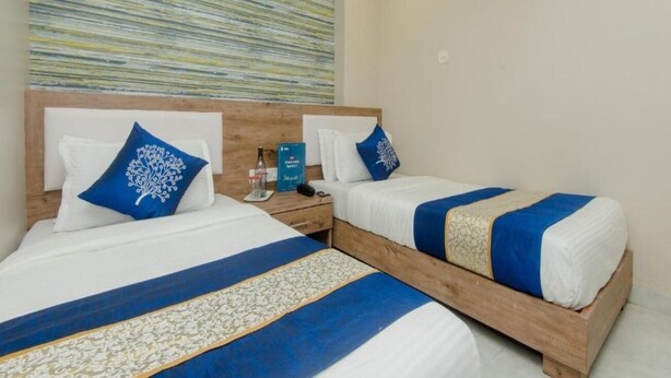 Habitación de hotel con dos camas, cada una con cubrecama azul y blanco, cabeceros de madera y un aire acondicionado instalado en la pared.